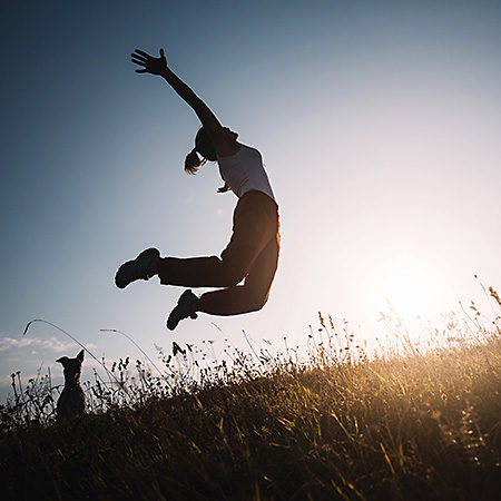 Silhouette of a woman jumping for joy against the sky.
